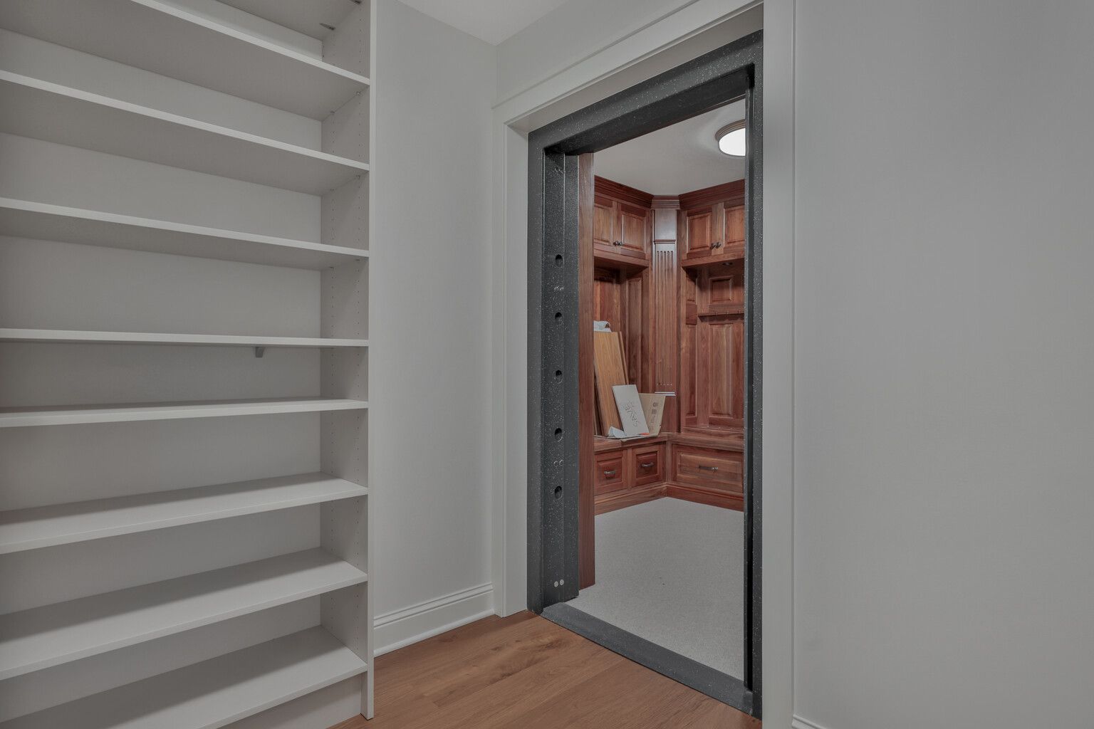 A walk in closet with shelves and a door leading to a vault.
