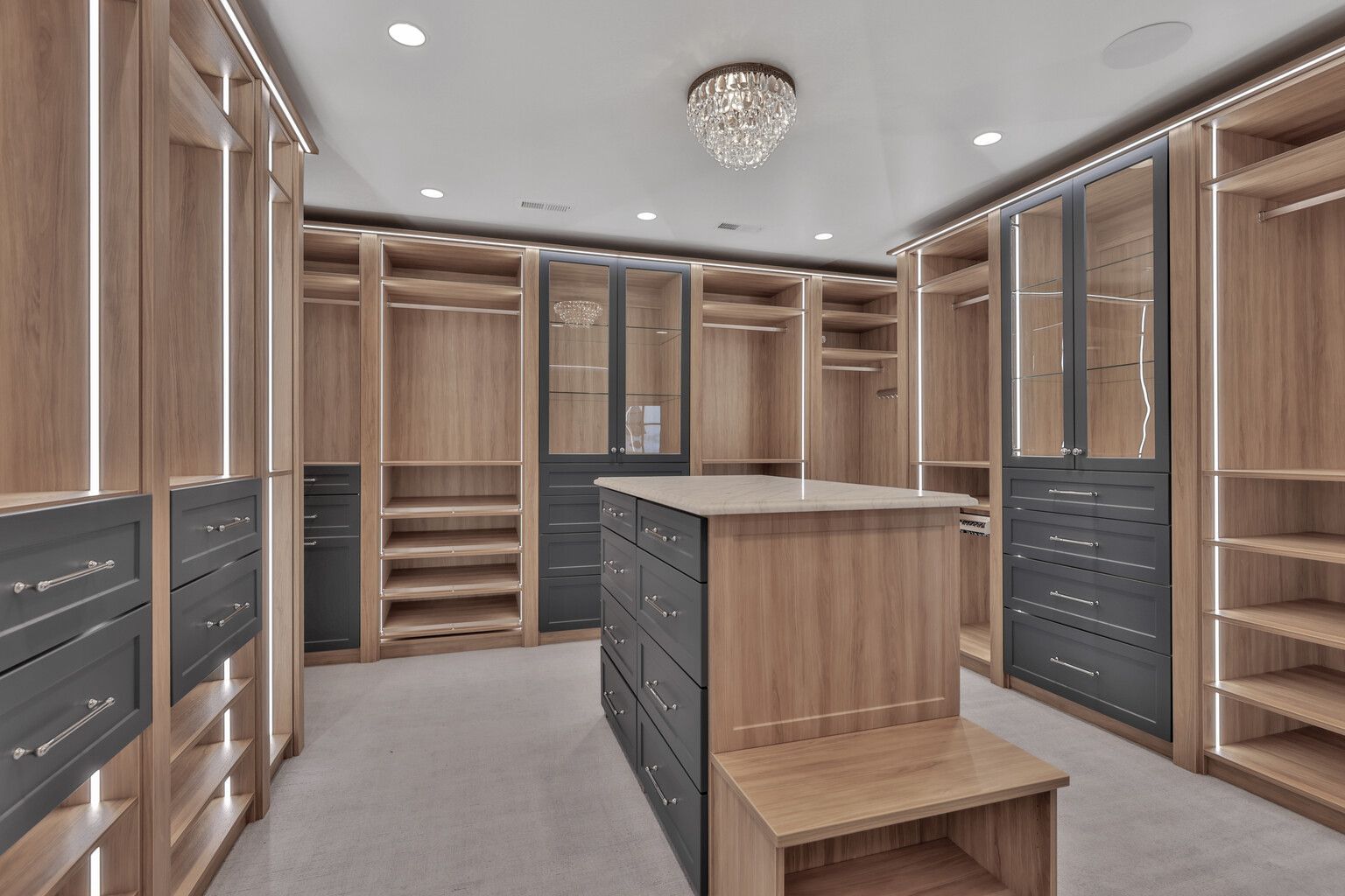 A large walk in closet with lots of wooden shelves and drawers.