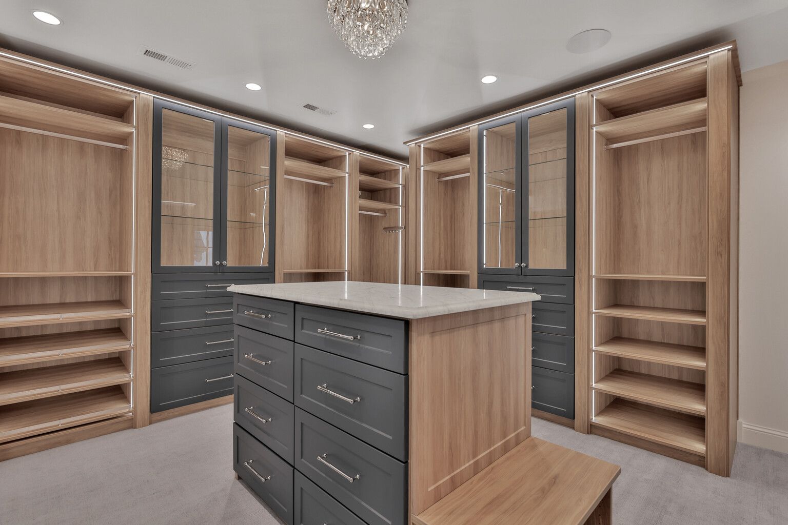 A large walk in closet with a large island in the middle.