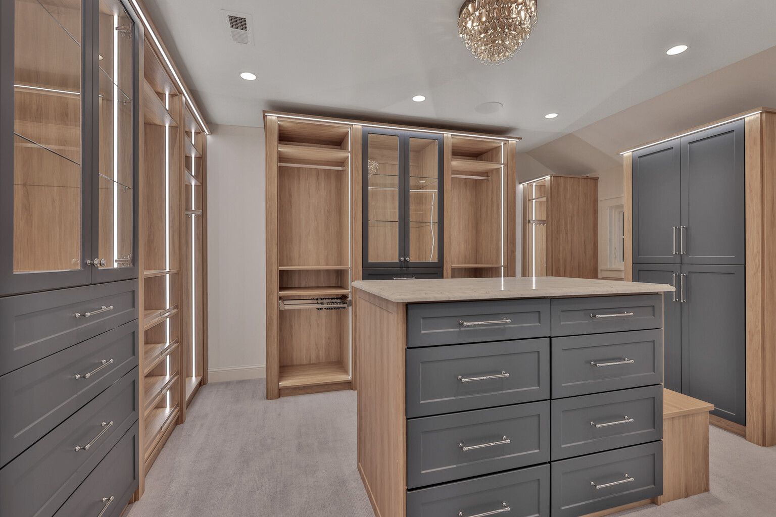 A large walk in closet with lots of drawers and cabinets.