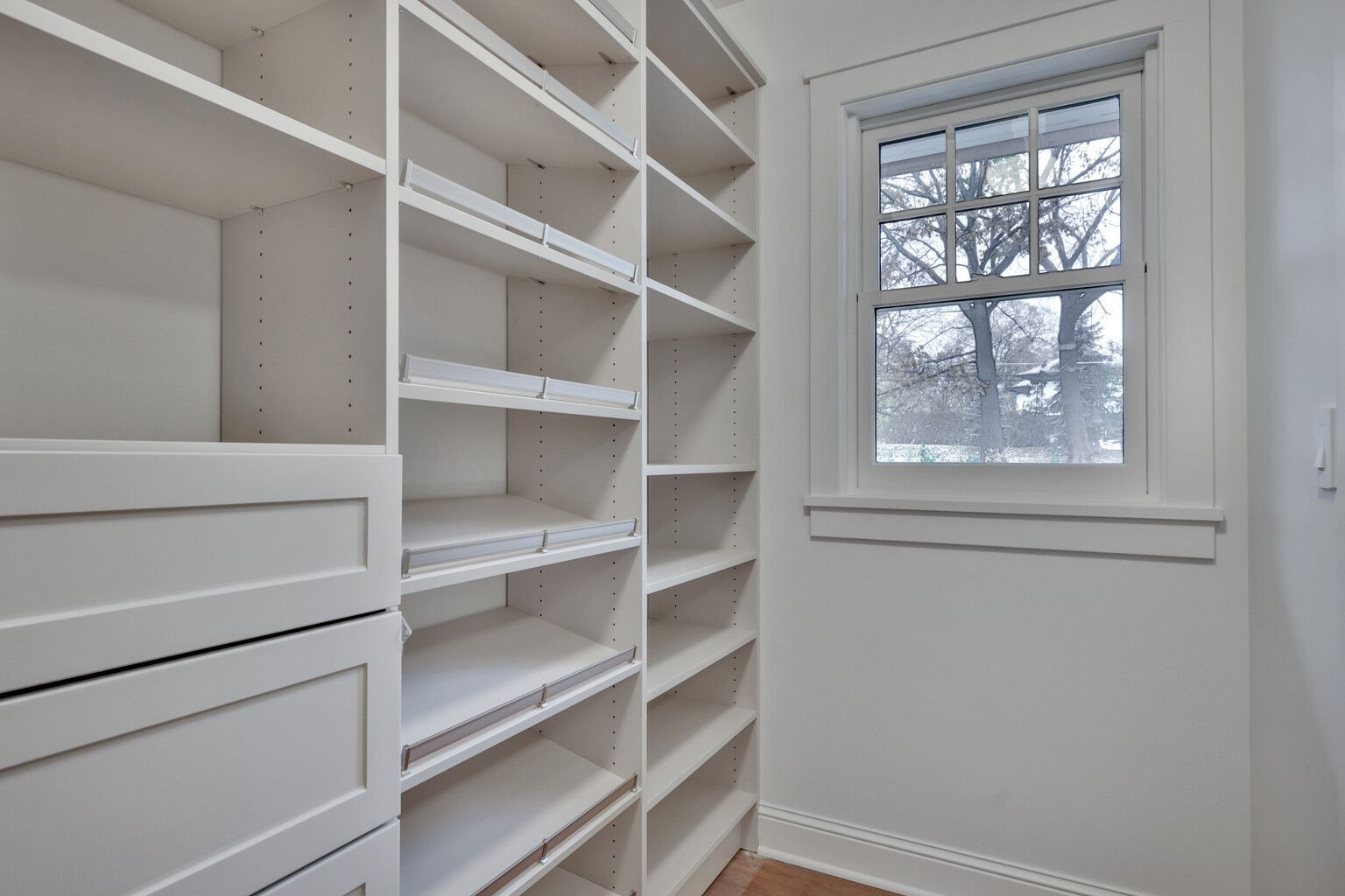 A walk in closet with lots of shelves and a window.