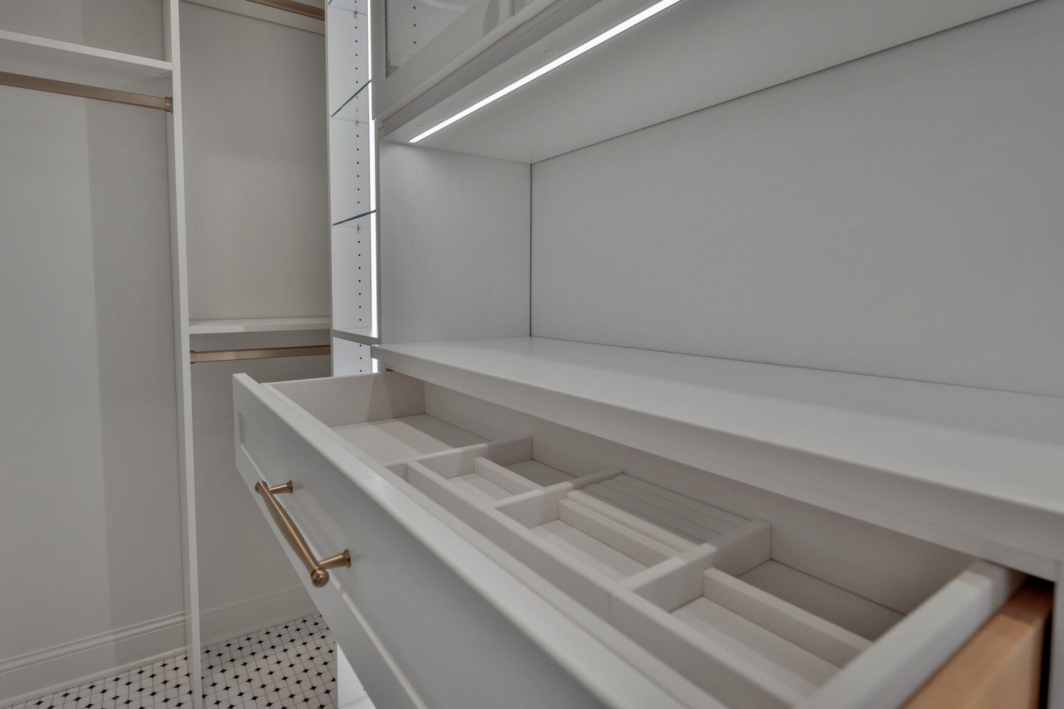 A walk in closet with a drawer filled with jewelry.