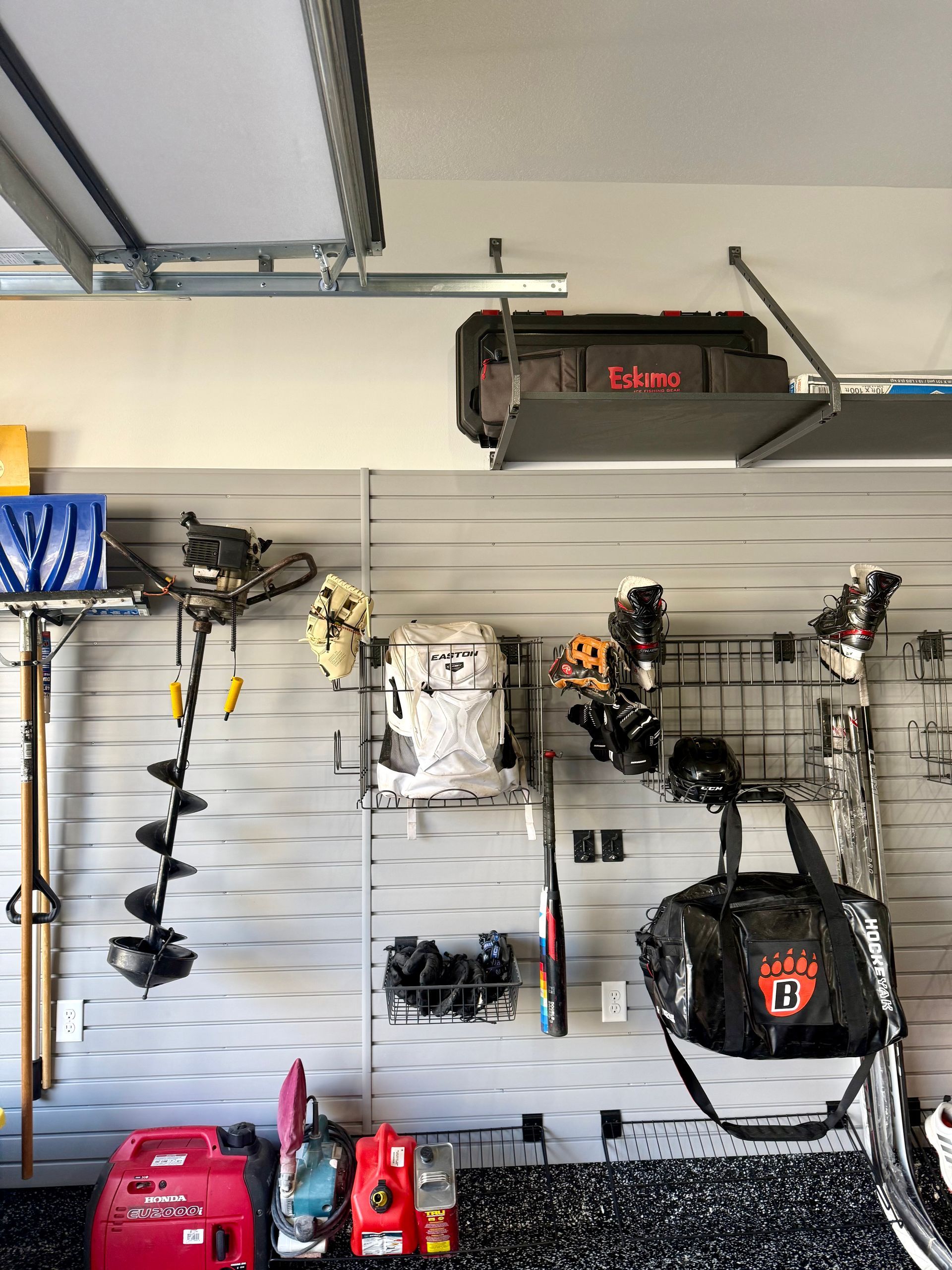 Garage wall with hanging tools and yard equipment, plus red machinery on the floor