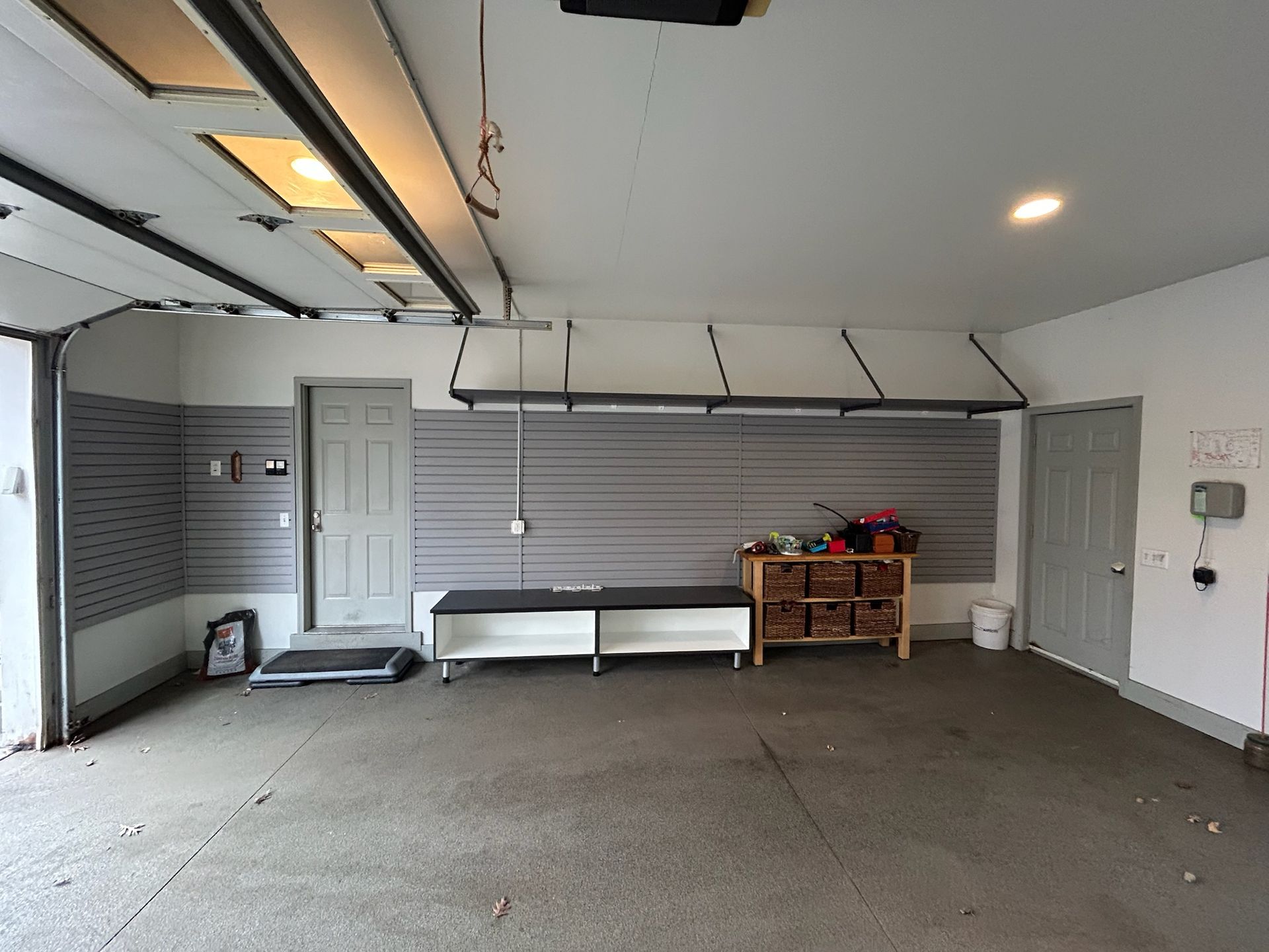 Empty garage with closed gray doors, white walls, and a workbench along the back wall