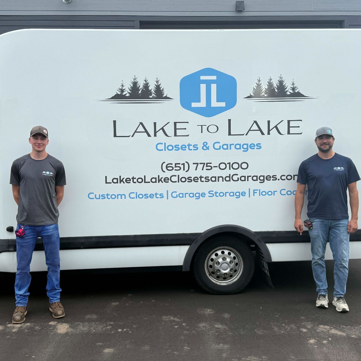 Two men stand in front of a white van with the company logo
