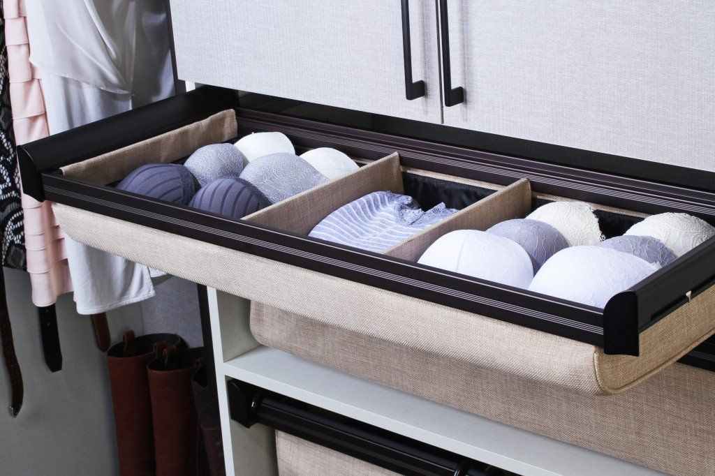 A pull-out drawer with socks organized into three compartments. The drawer is beige with a dark brown frame, inside a closet.