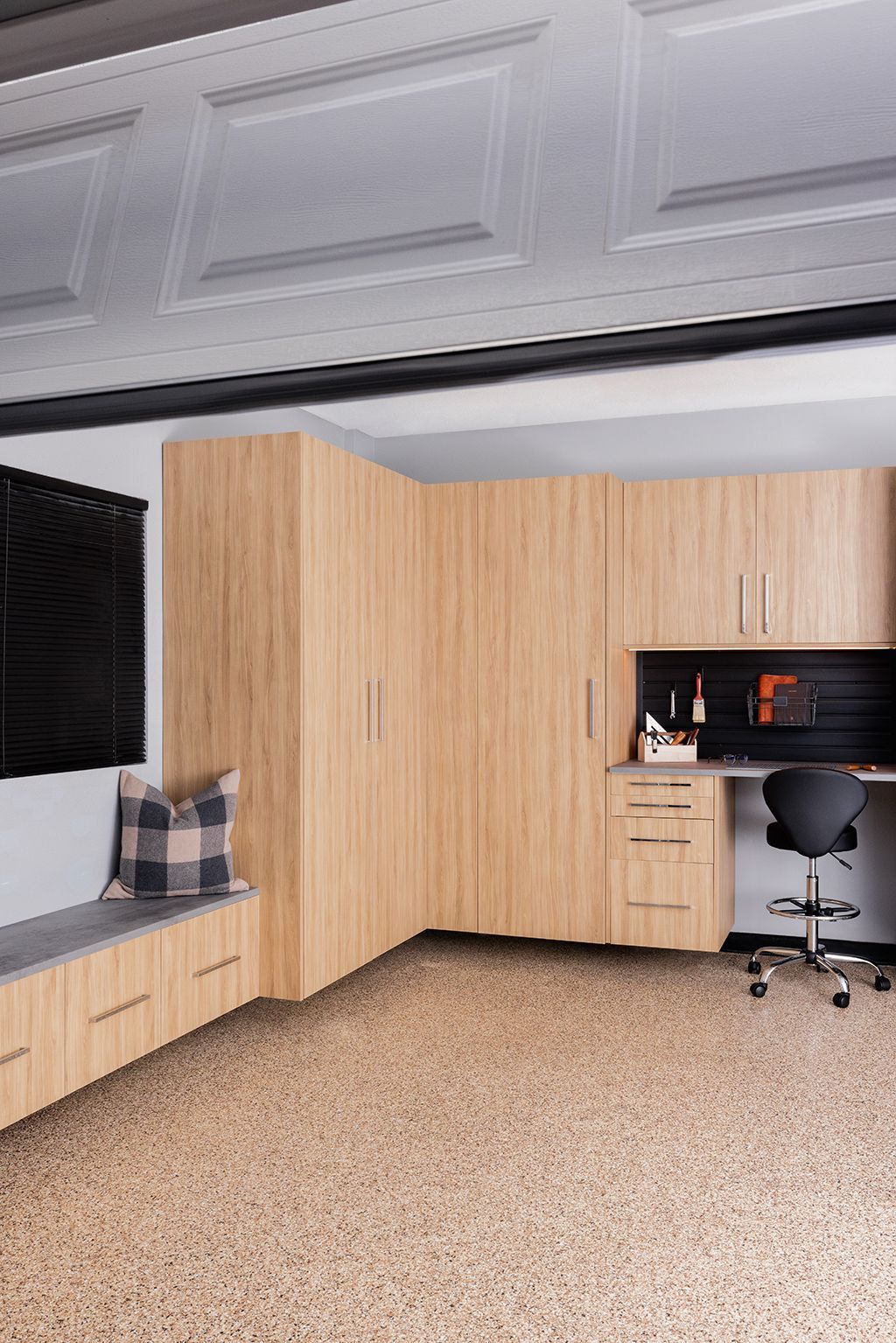 A garage with wooden cabinets , a workbench and a chair.