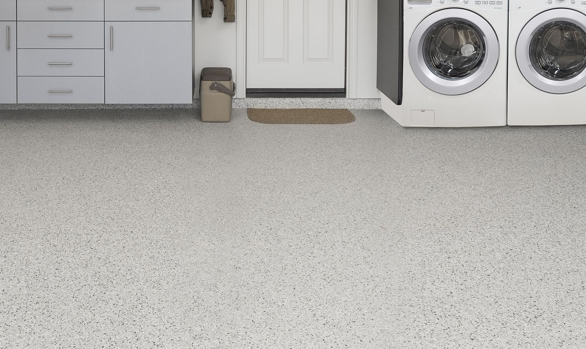 A laundry room/garage with a washer and dryer on the floor.