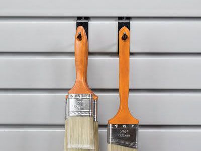 A rake and a shovel are hanging on a wall.