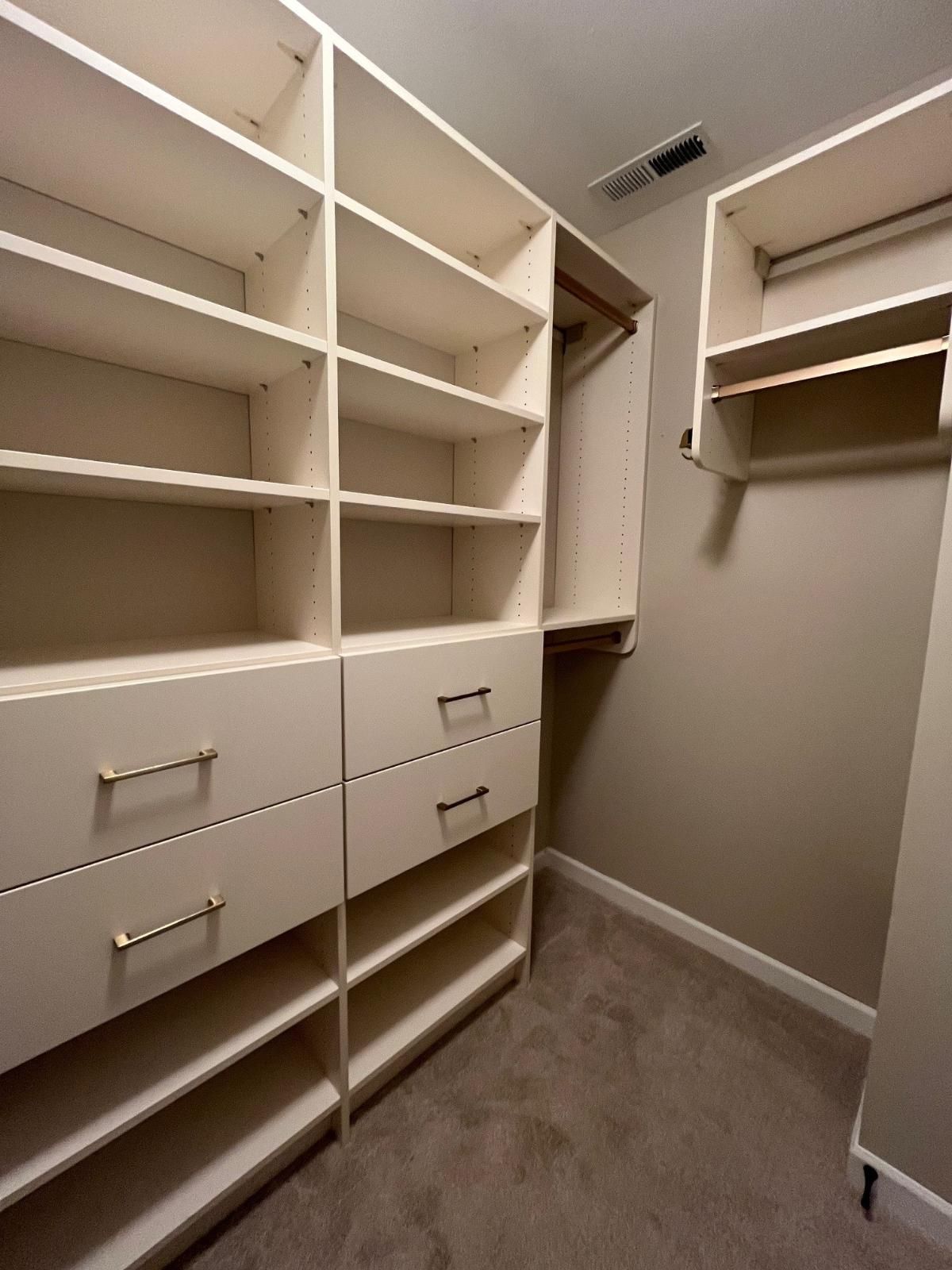 A walk in closet with lots of shelves and drawers.