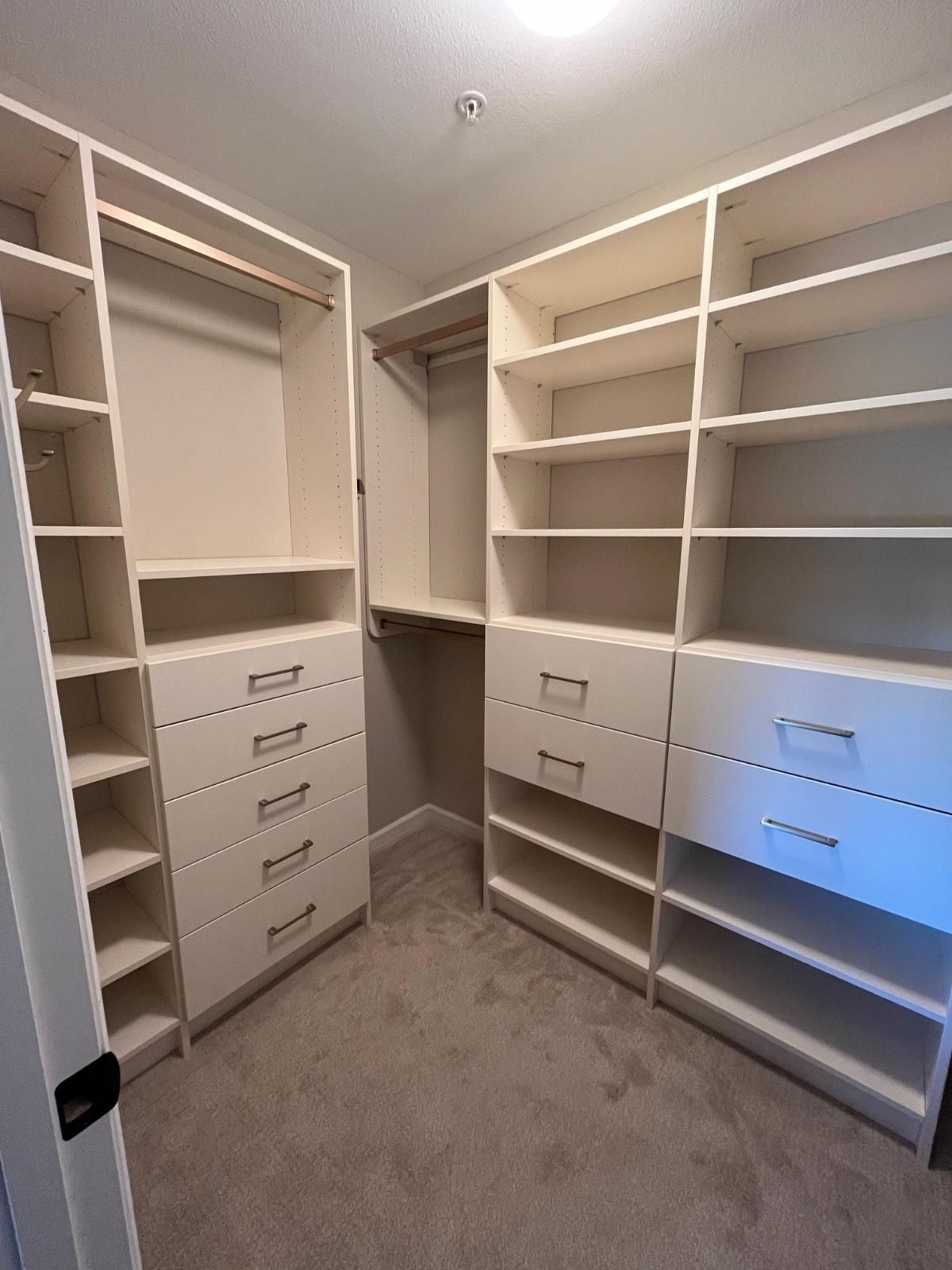 A walk in closet with lots of shelves and drawers.