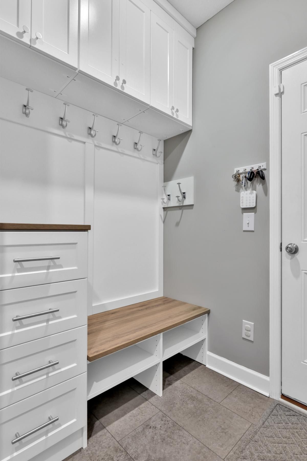 A mud room with white cabinets and a wooden bench.