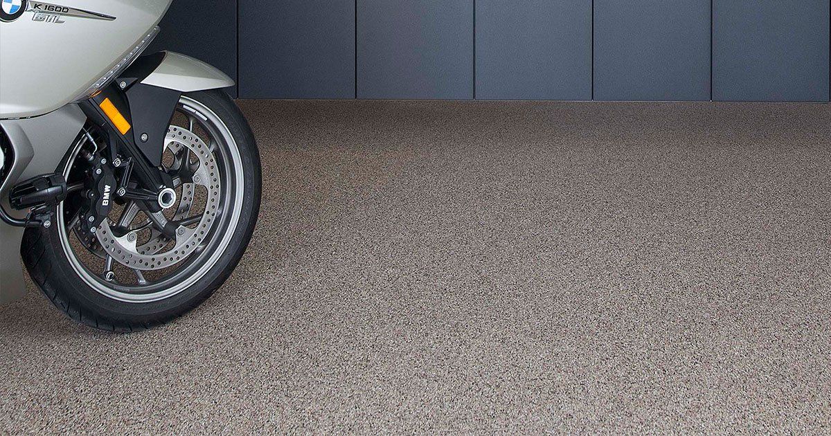 A motorcycle is parked on a coated floor in a garage.