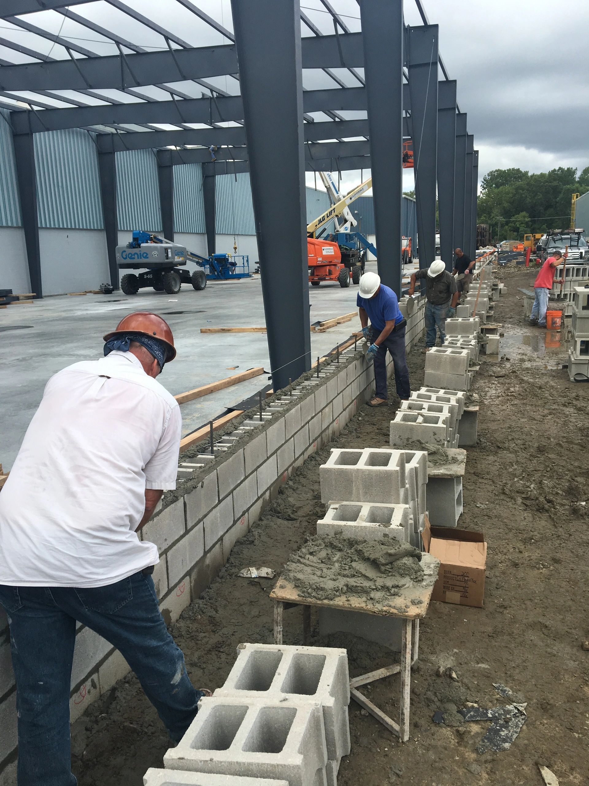 A group of construction workers are working on a brick wall