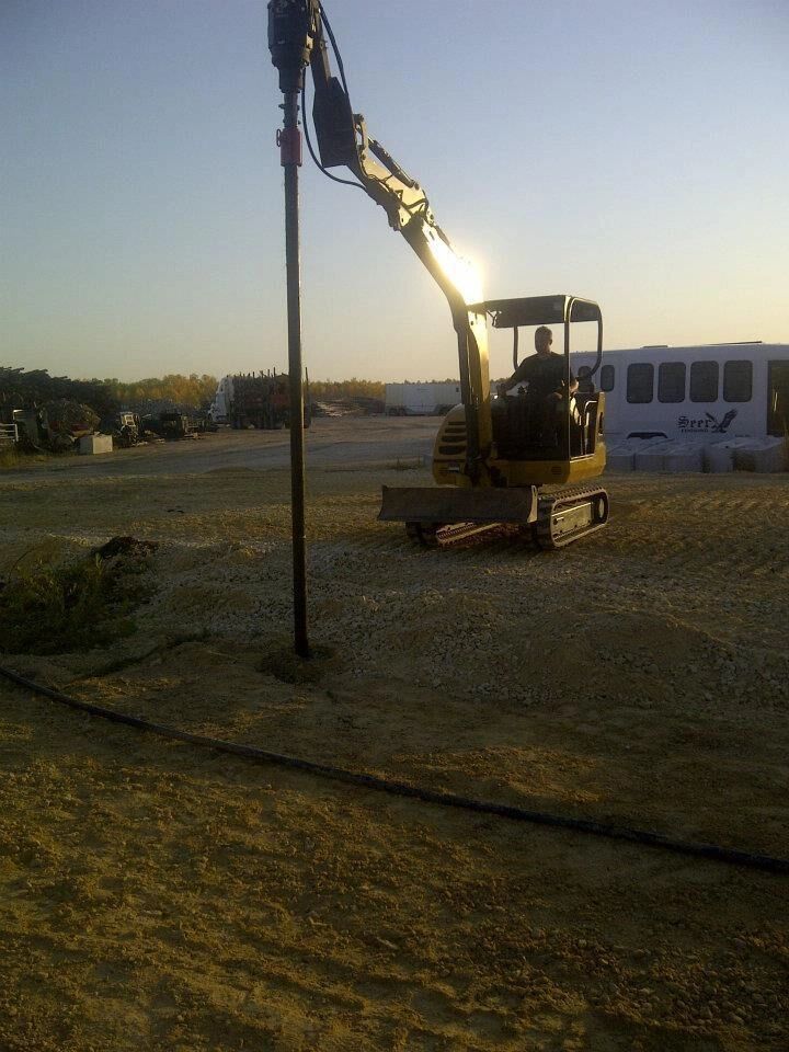 A man is driving an excavator in a dirt field