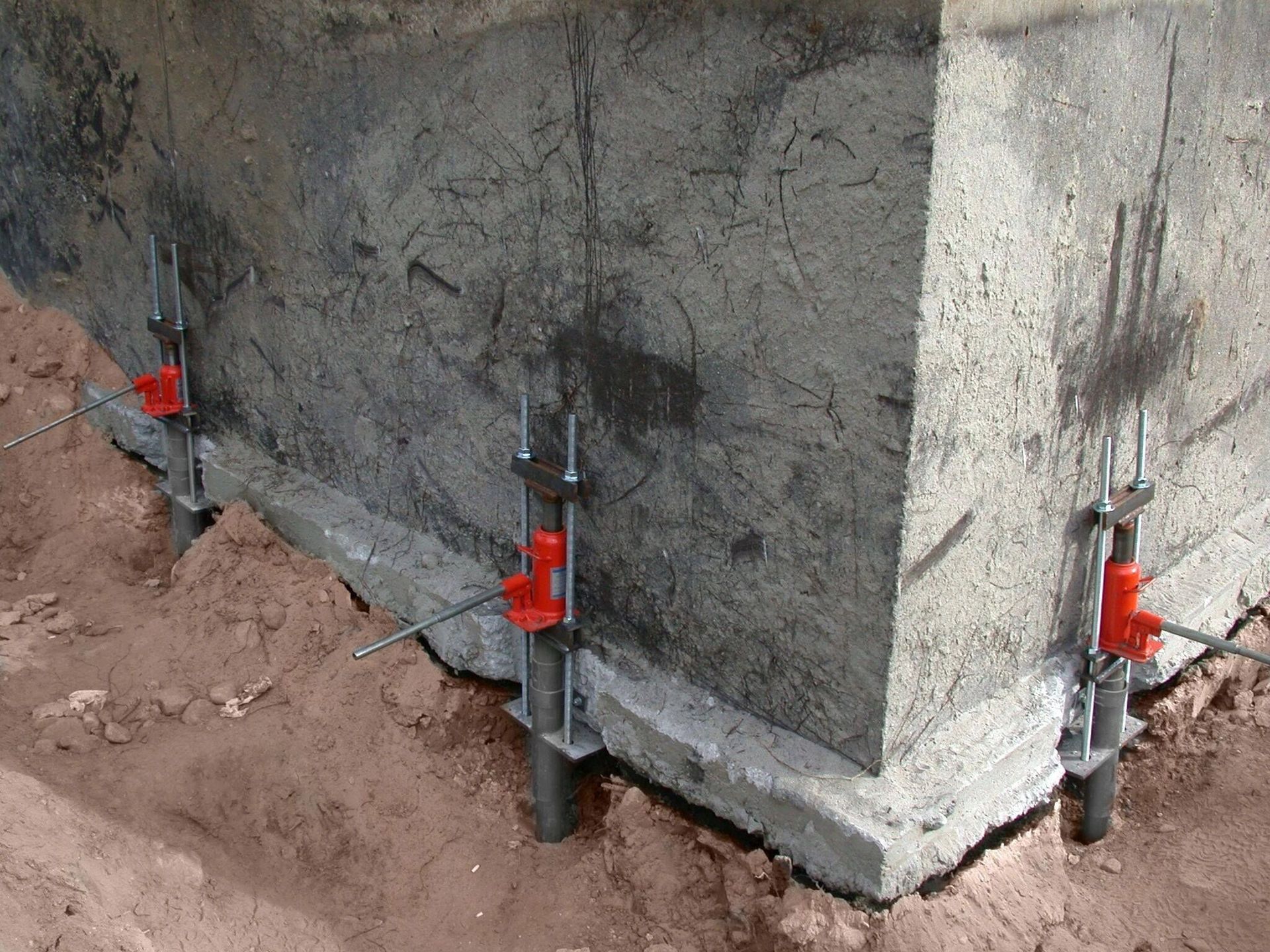 A corner of a concrete wall with red clips attached to it.