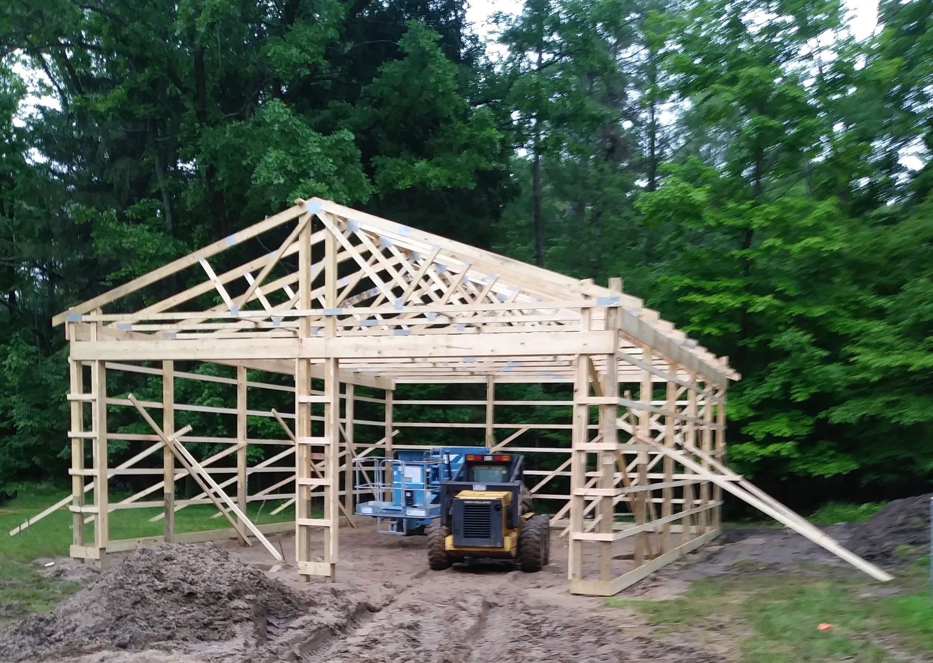 A tractor is parked in front of a wooden building under construction.