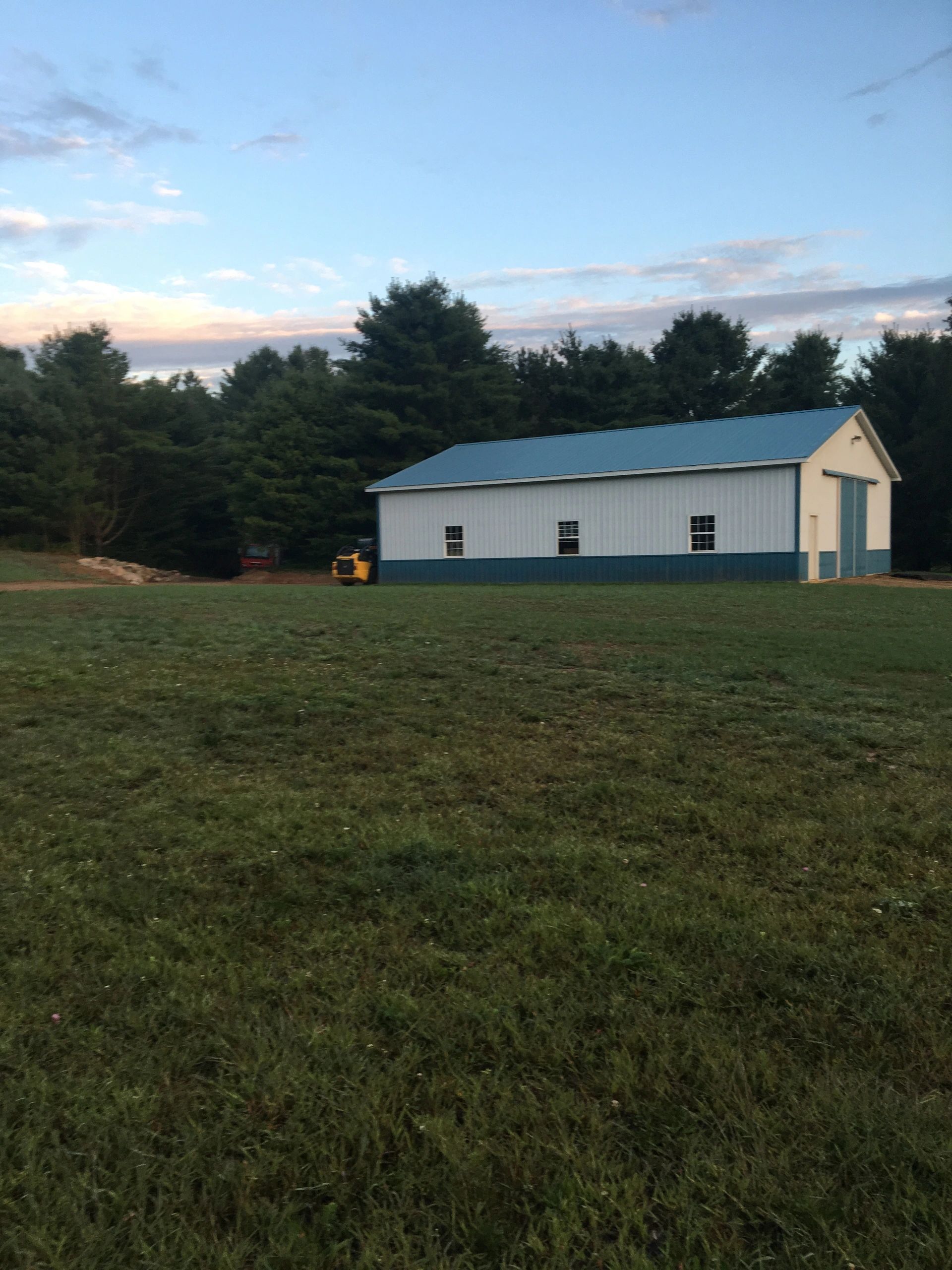 A white building with a blue roof is in the middle of a grassy field.