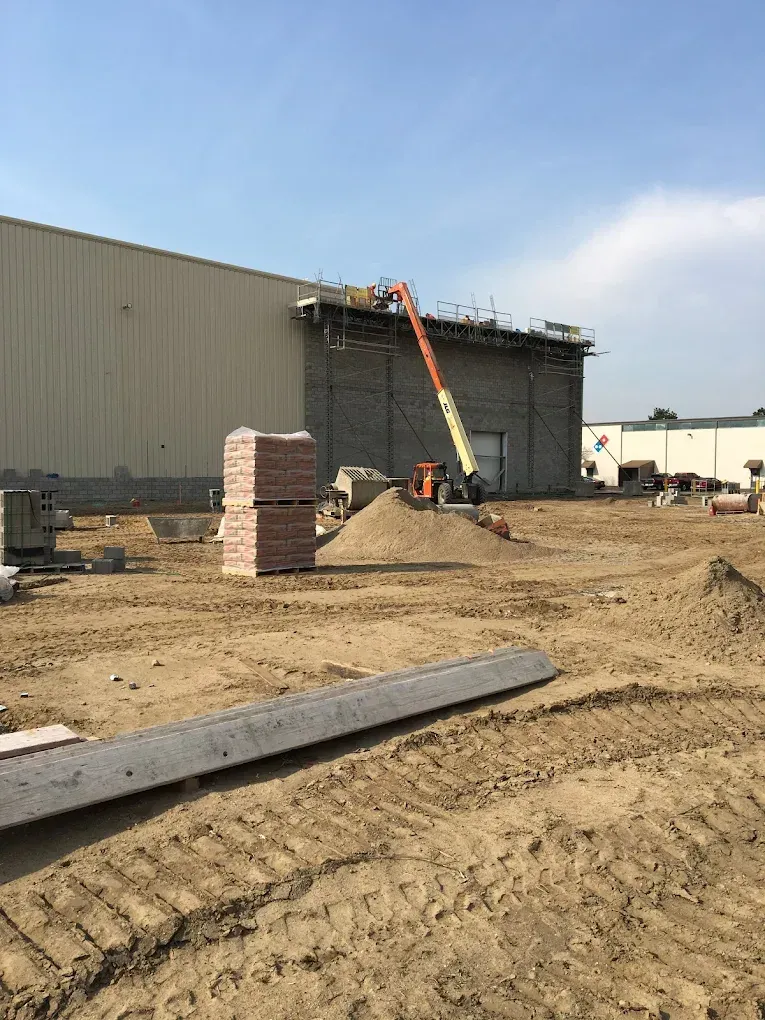 A large building is being built in a dirt field.