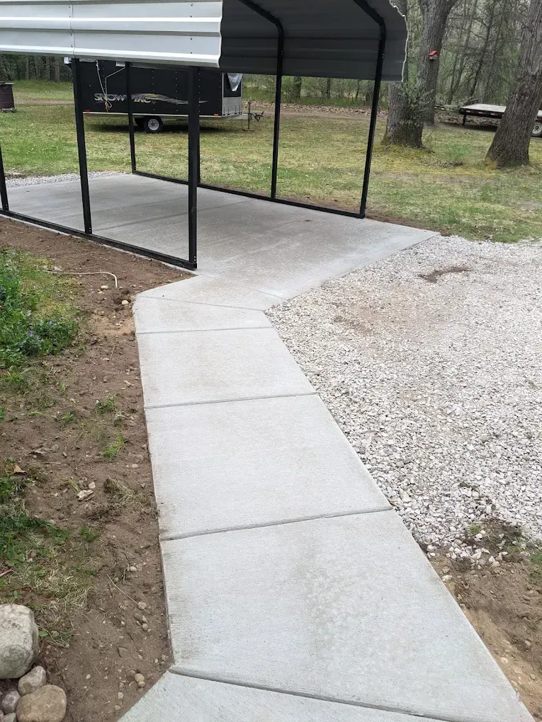 A concrete walkway leading to a carport with a canopy over it