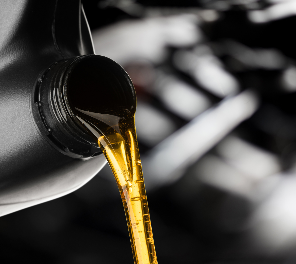 A bottle of oil is being poured into a car engine
