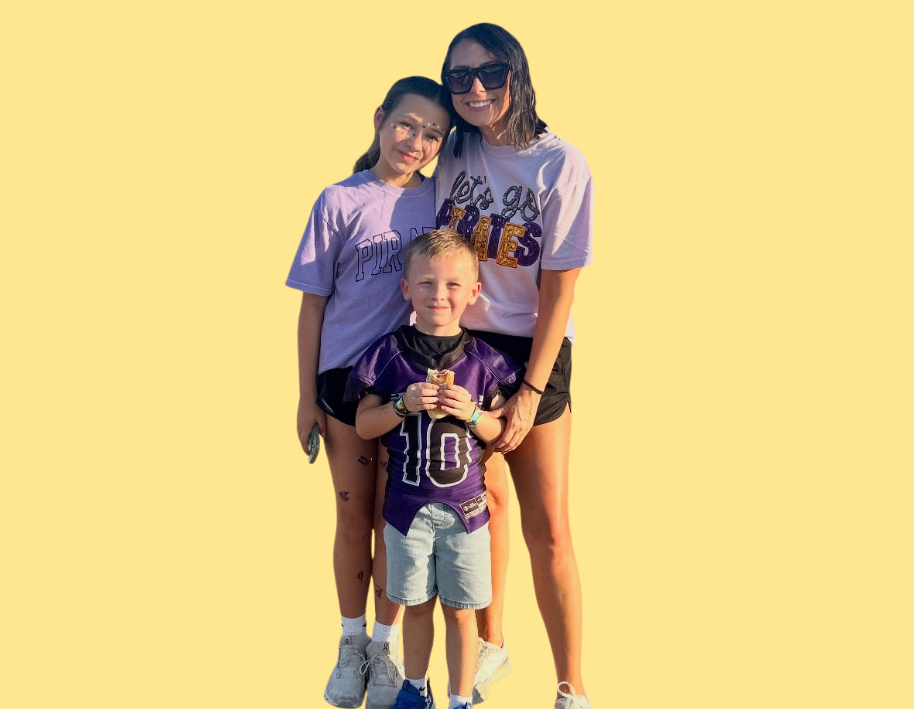 Man in green polo stands on a football field, arms crossed, stadium in background.