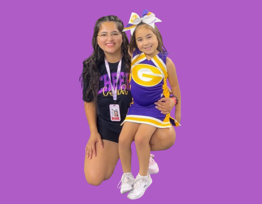Man in green polo stands on a football field, arms crossed, stadium in background.