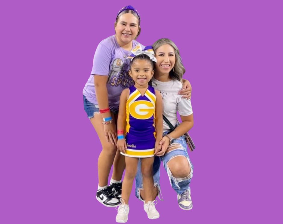 Man with crossed arms on a football field. He is wearing a blue polo shirt, khaki pants, and has a serious expression.