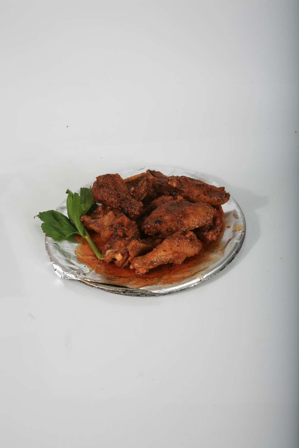 A plate of chicken wings with sauce and parsley on a table.