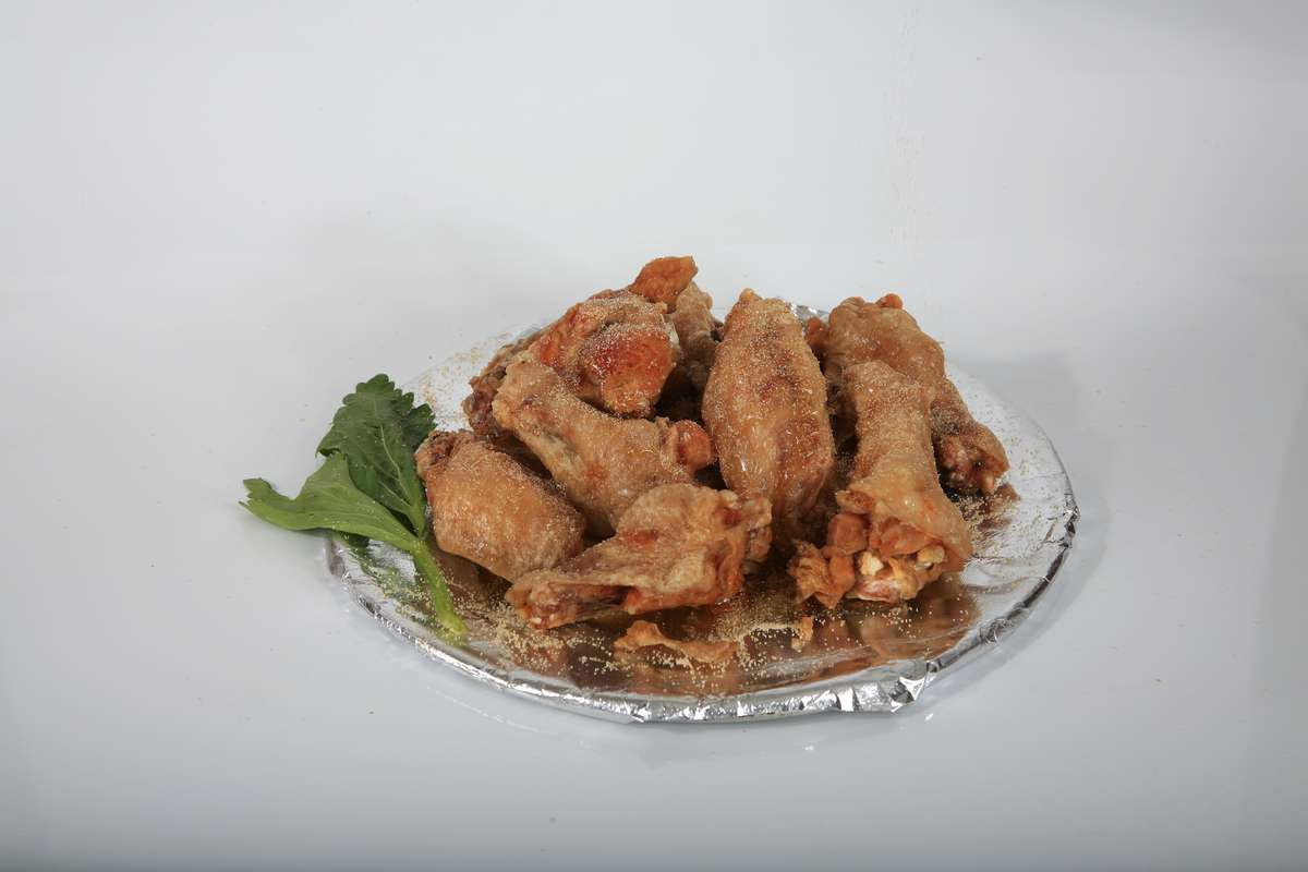 A plate of fried chicken wings with lettuce on a white background.