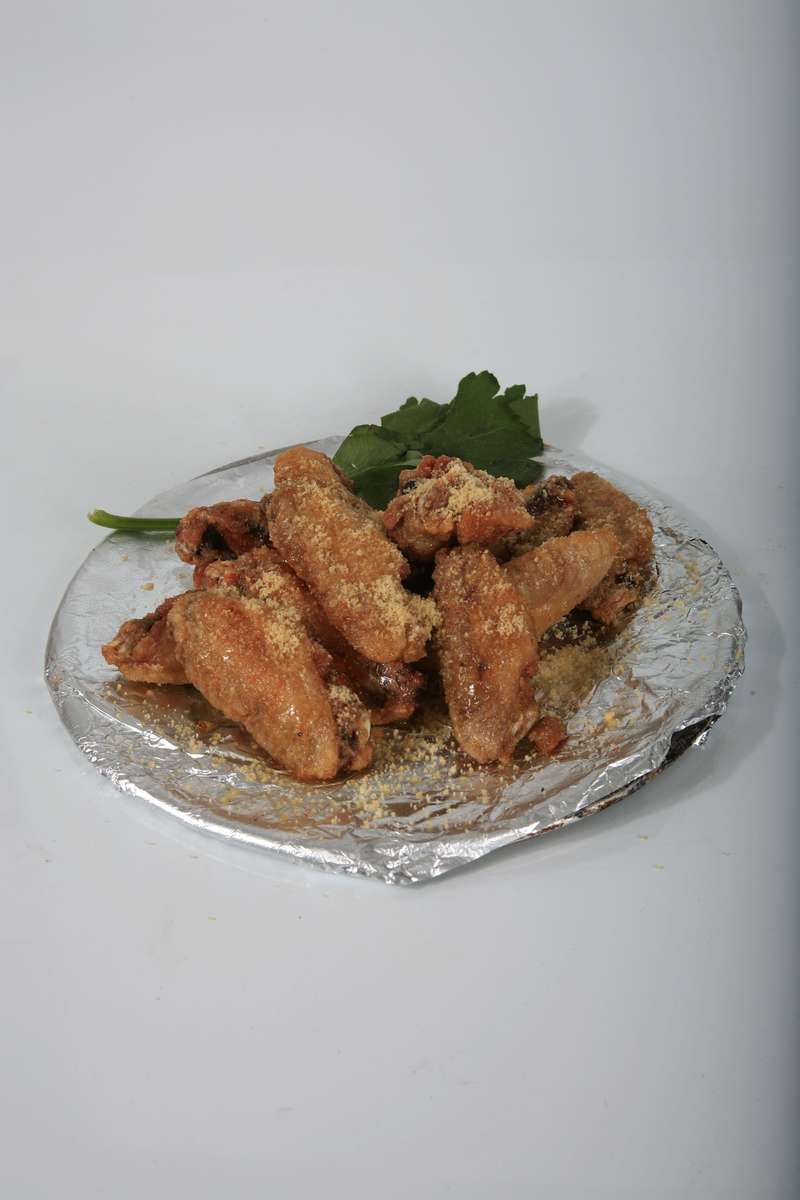 A close up of a plate of fried chicken wings on a table.