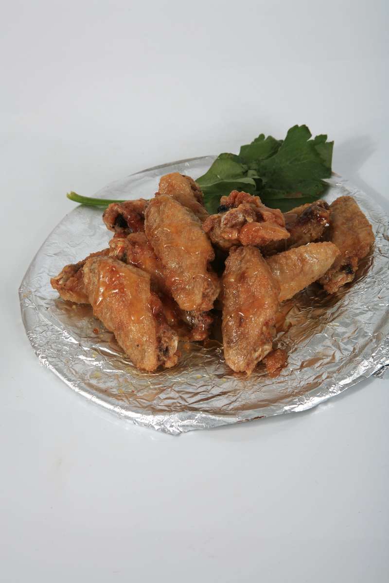 A plate of chicken wings with parsley on a white background.