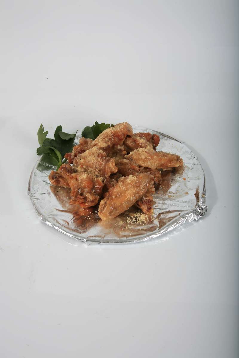 A plate of fried chicken wings with parsley on a white background.