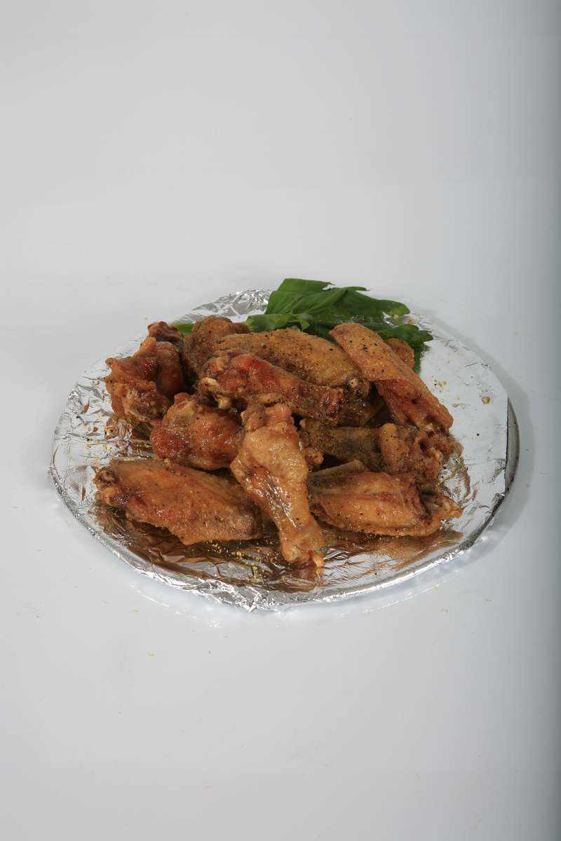 A close up of a plate of chicken wings on a table.