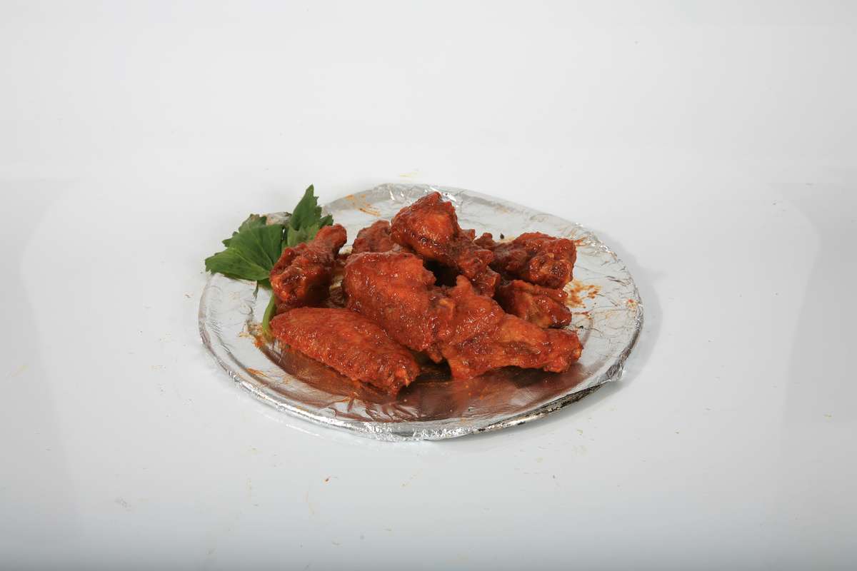 A close up of a plate of chicken wings on a white background.