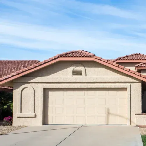 A house with a large garage door and a red tile roof.