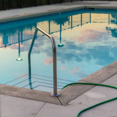 This is a picture of a beautifully 
 sparkling pool, reflecting the fluffy clouds at mid day.