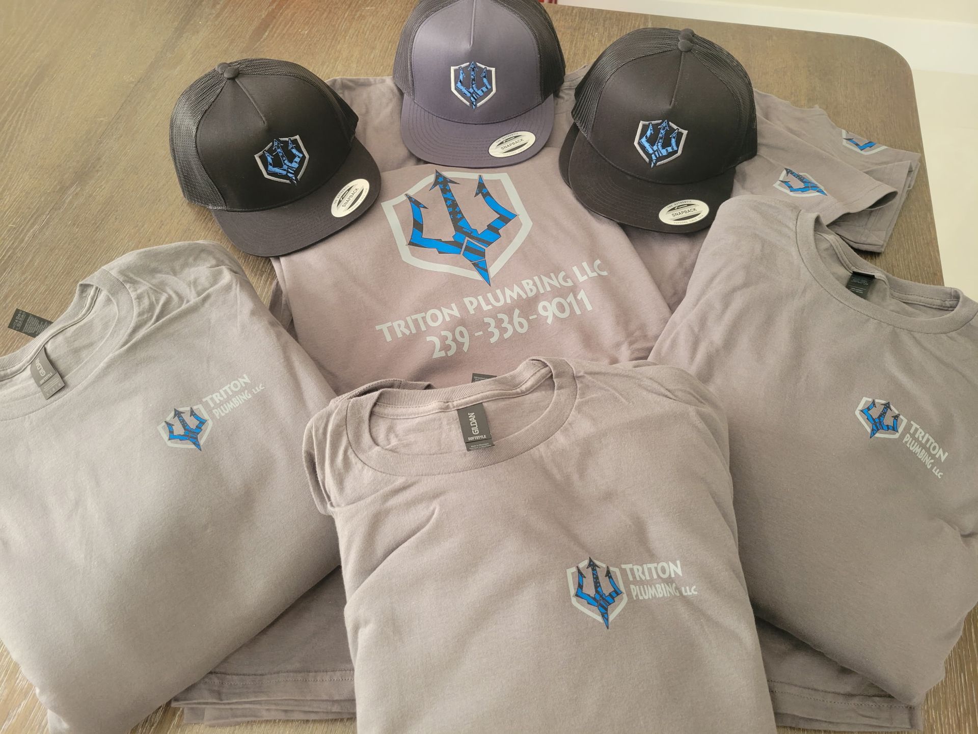 A bunch of shirts and hats are sitting on a table.