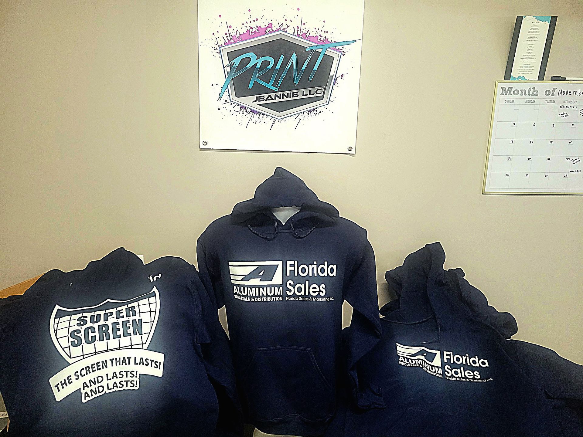 Three hoodies are displayed in front of a sign that says print