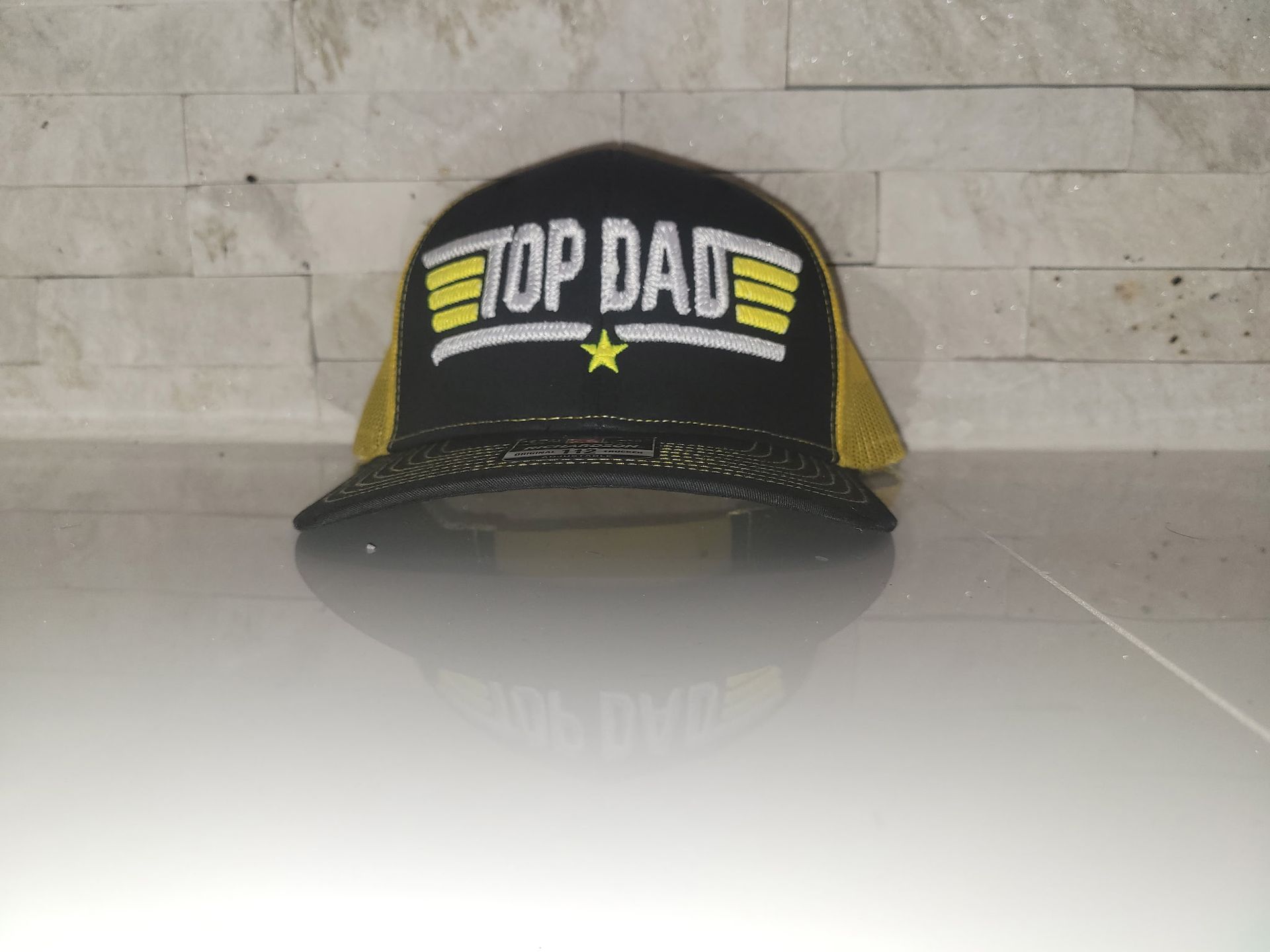 A black and yellow top dad hat is sitting on a white surface