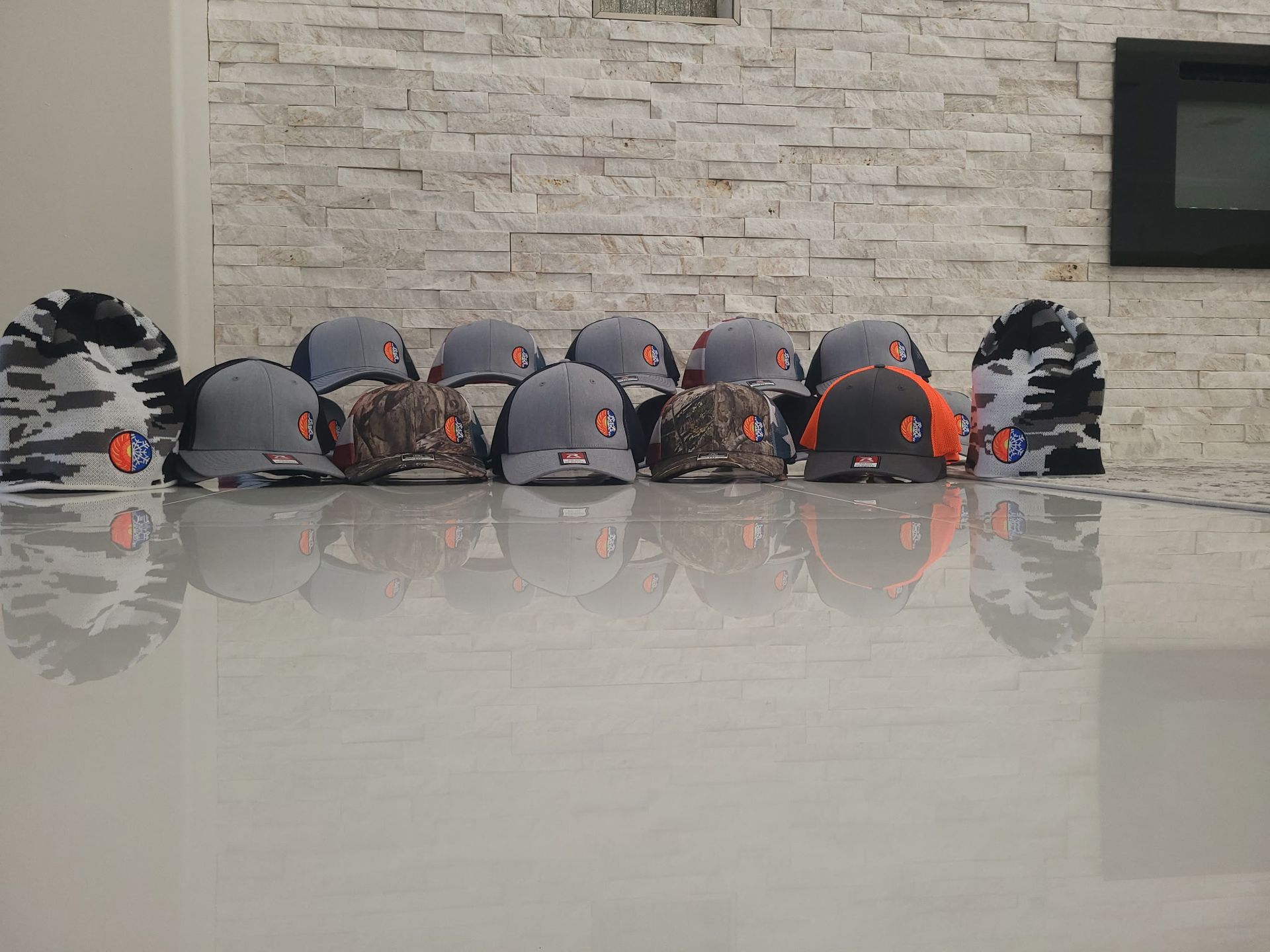 A bunch of hats are sitting on a table in front of a brick wall.