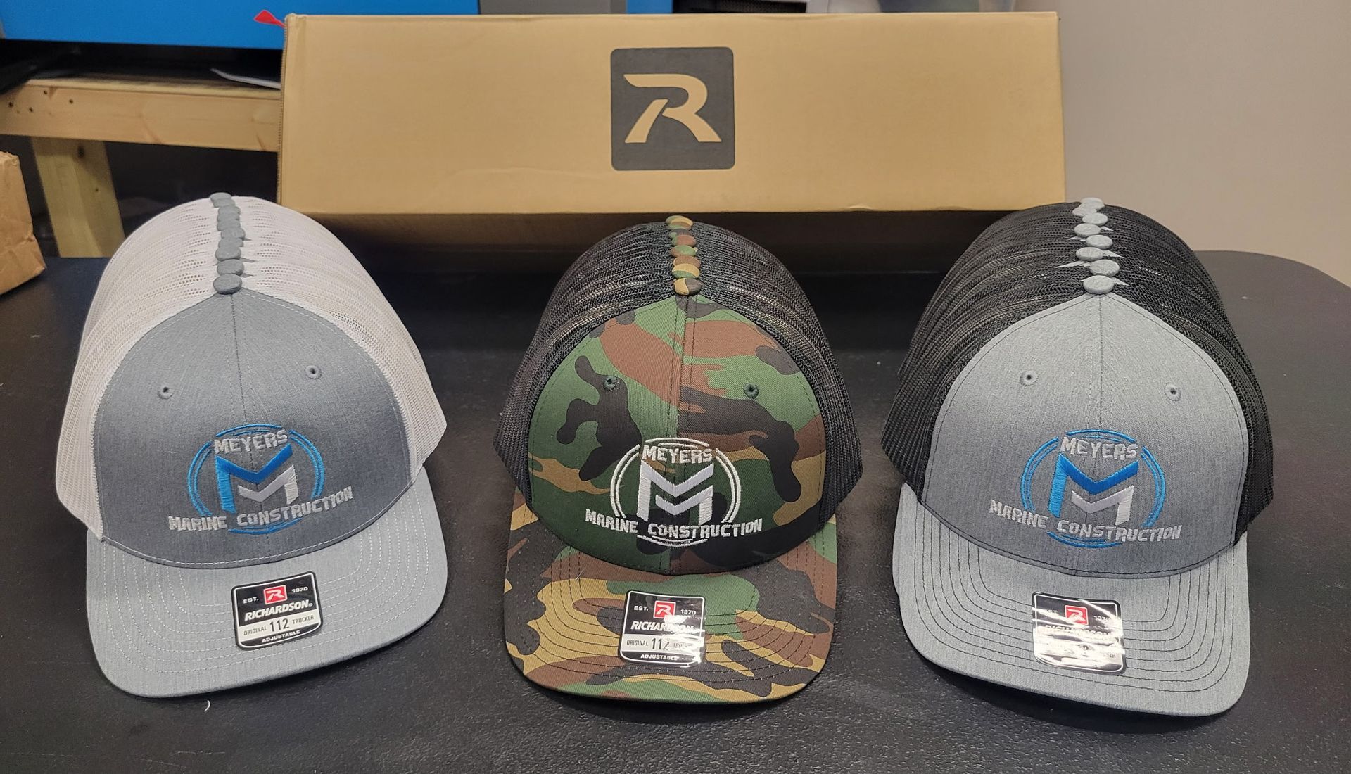 Three hats are sitting on a table in front of a box.