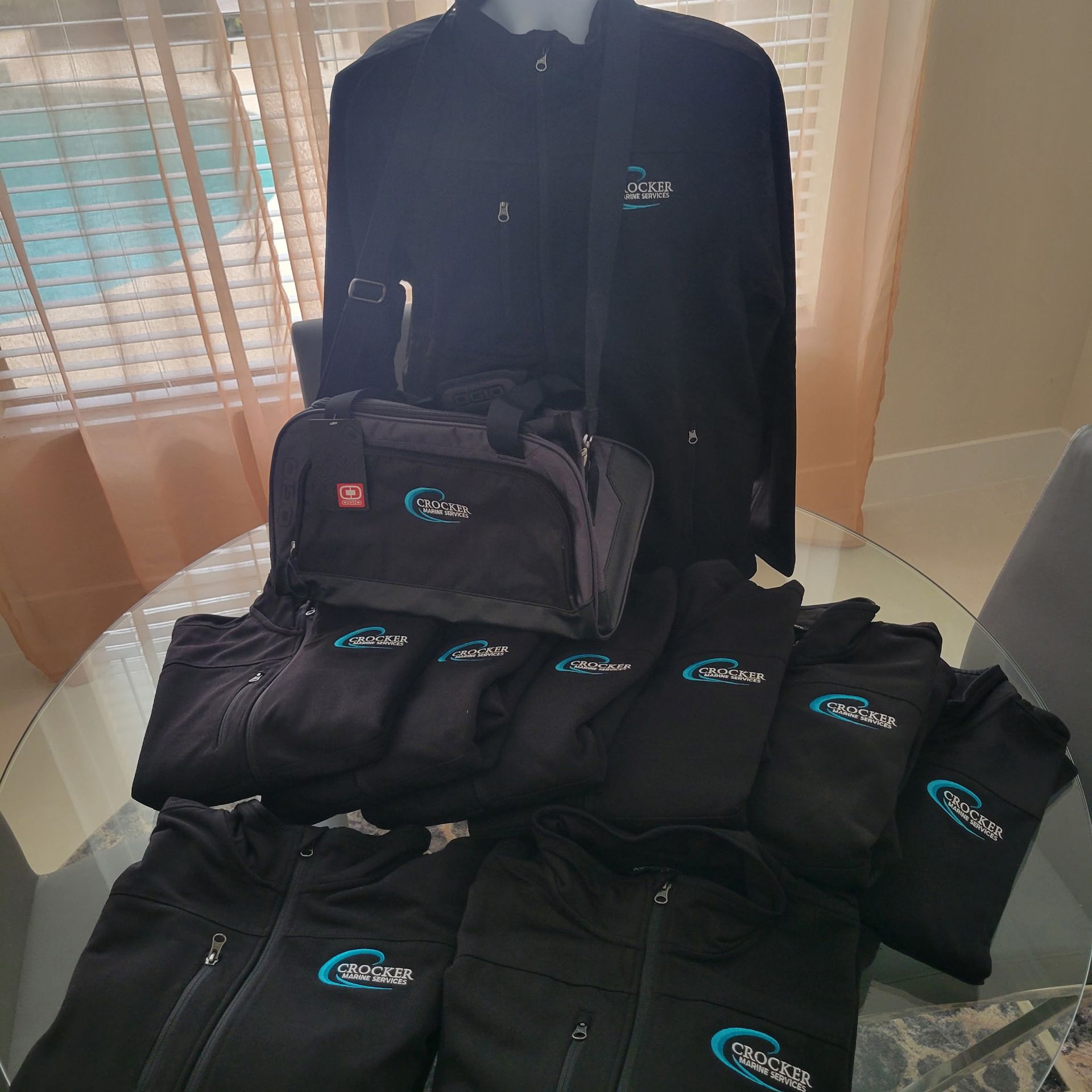 A group of black shirts and a black bag are sitting on a table.