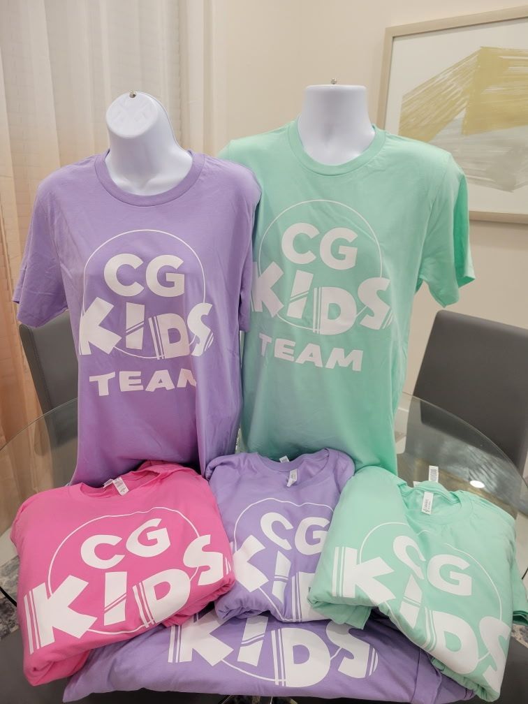 A bunch of cg kids team shirts are sitting on a table