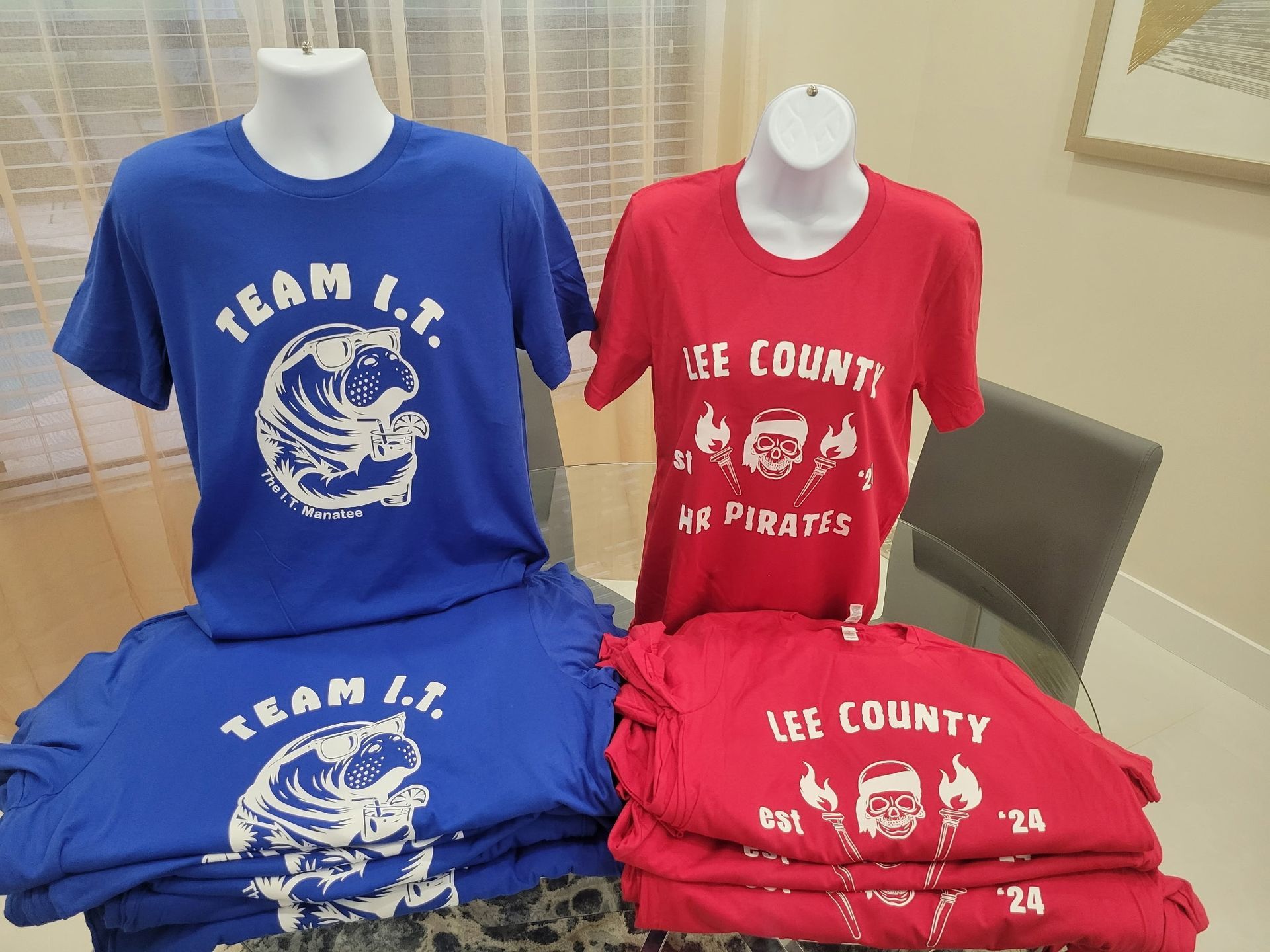 A stack of lee county pirates t-shirts on a table
