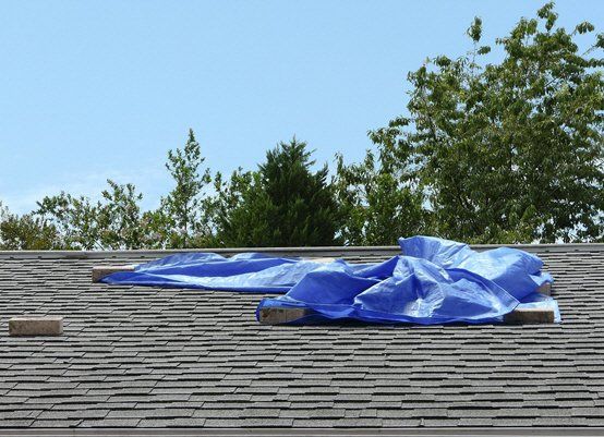 A blue tarp is laying on top of a roof