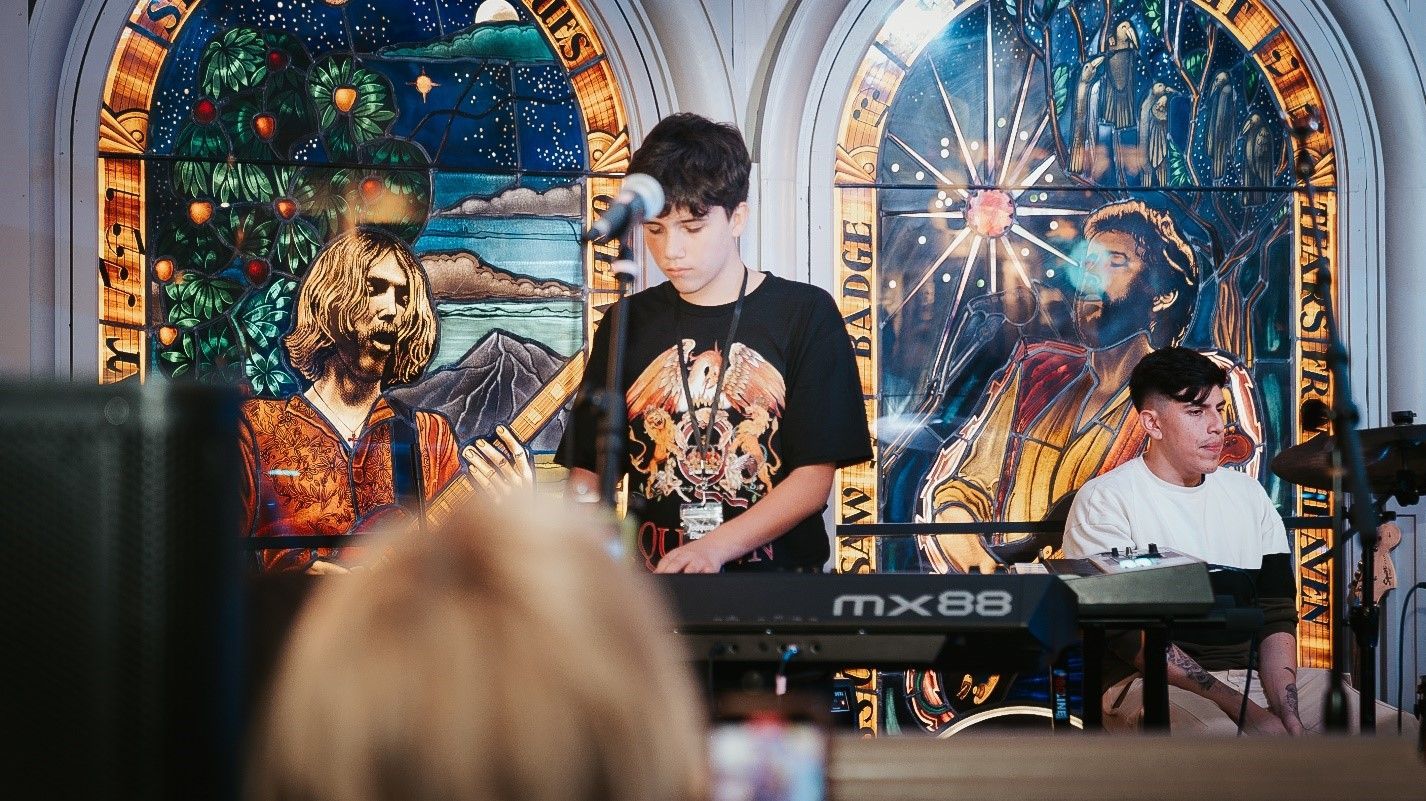 A boy playing guitar in front of a crowd