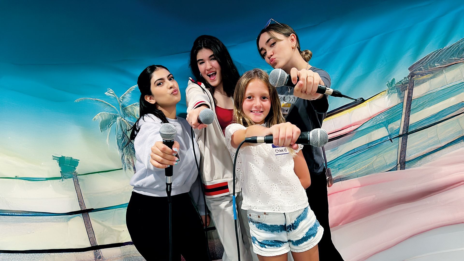 Four girls holding microphones to the camera 