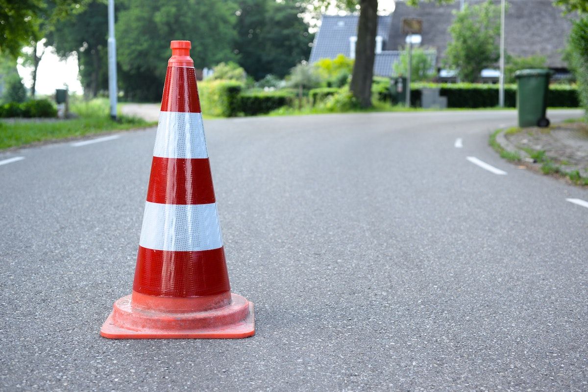 a red and white traffic cone is sitting on the side of a road .
