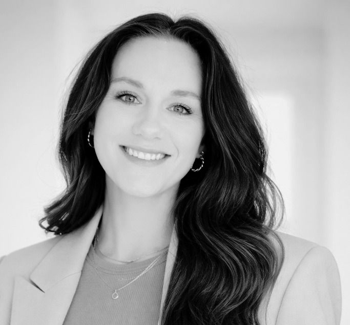A man in a suit and tie is smiling in a black and white photo.